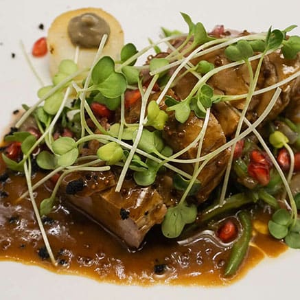 Gerecht met gestoofd vlees, verse kiemen, granaatappel en een romige jus.