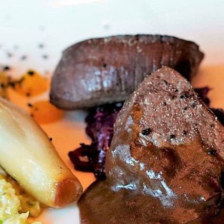 Twee stukken rosé gebakken vlees met rode kool, witlof en een puree.
